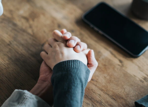 Close up of young couple holding hands on coffee table.